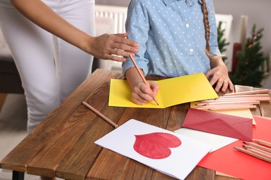 Photo of Little girl with her mother making beautiful greeting card at home, closeup