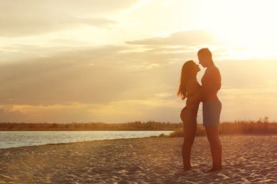 Photo of Young woman in bikini spending time with her boyfriend on beach. Lovely couple