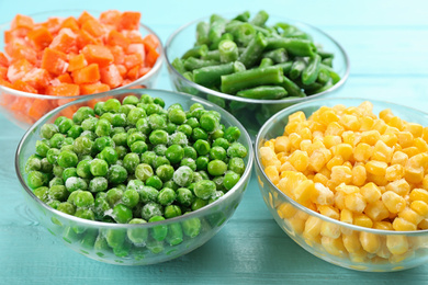 Photo of Different tasty frozen vegetables on light blue wooden table