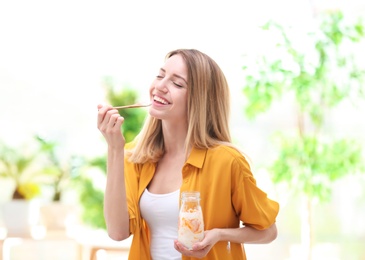 Photo of Young attractive woman eating tasty yogurt, indoors