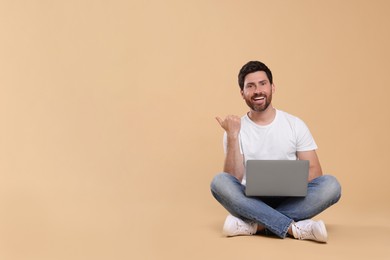 Happy man with laptop on beige background. Space for text