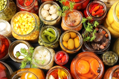 Photo of Open jars with pickled vegetables and dill inflorescences on grey table, flat lay
