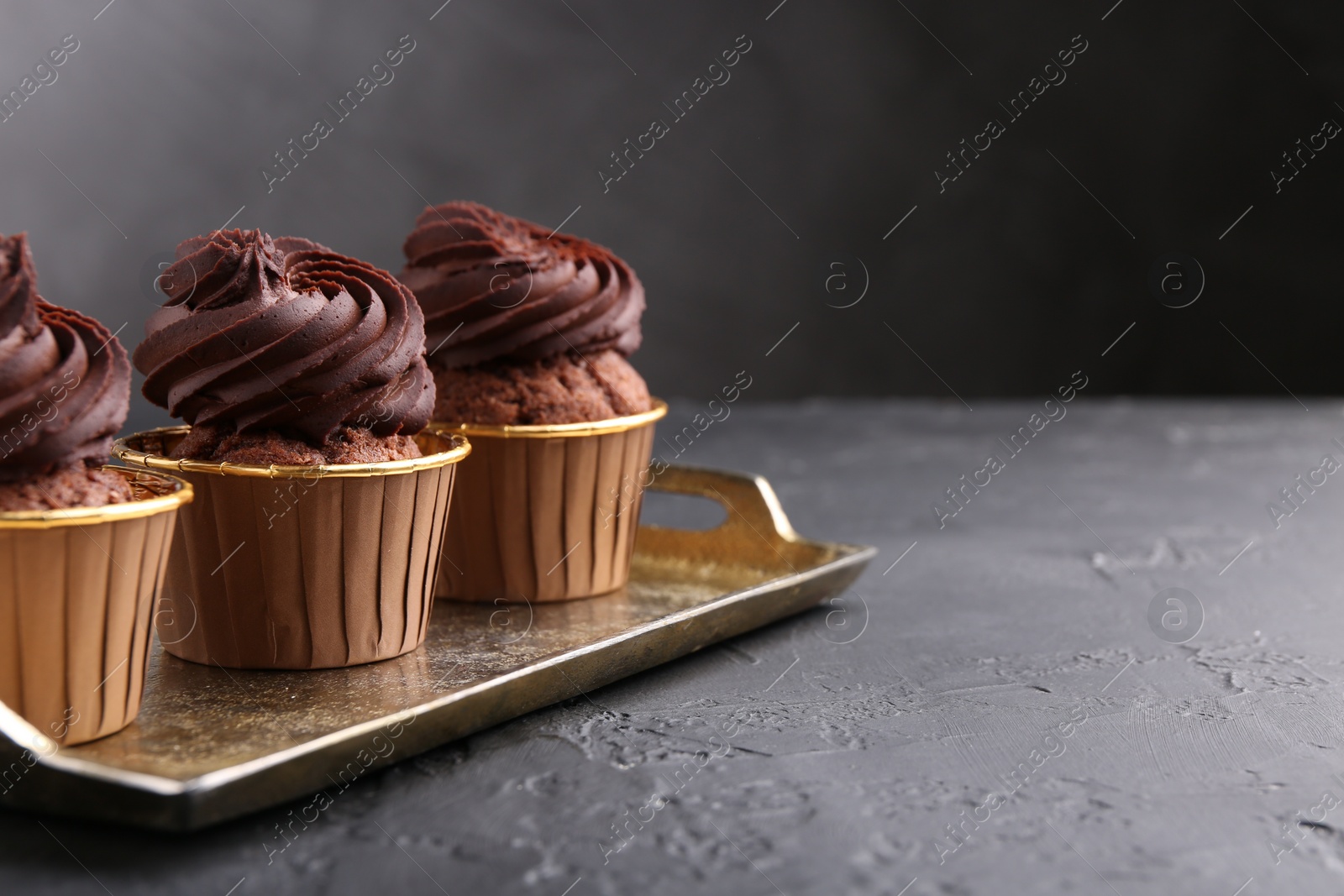 Photo of Delicious chocolate cupcakes on black textured table. Space for text