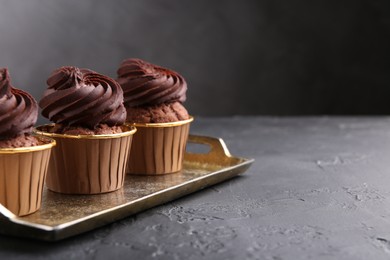 Delicious chocolate cupcakes on black textured table. Space for text