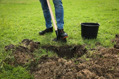 Photo of Worker digging soil with shovel outdoors, closeup