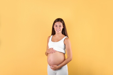 Photo of Happy pregnant woman posing on color background