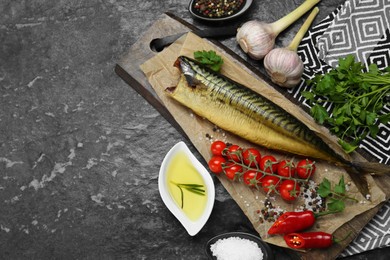 Photo of Delicious smoked mackerel and different products on black textured table, flat lay. Space for text