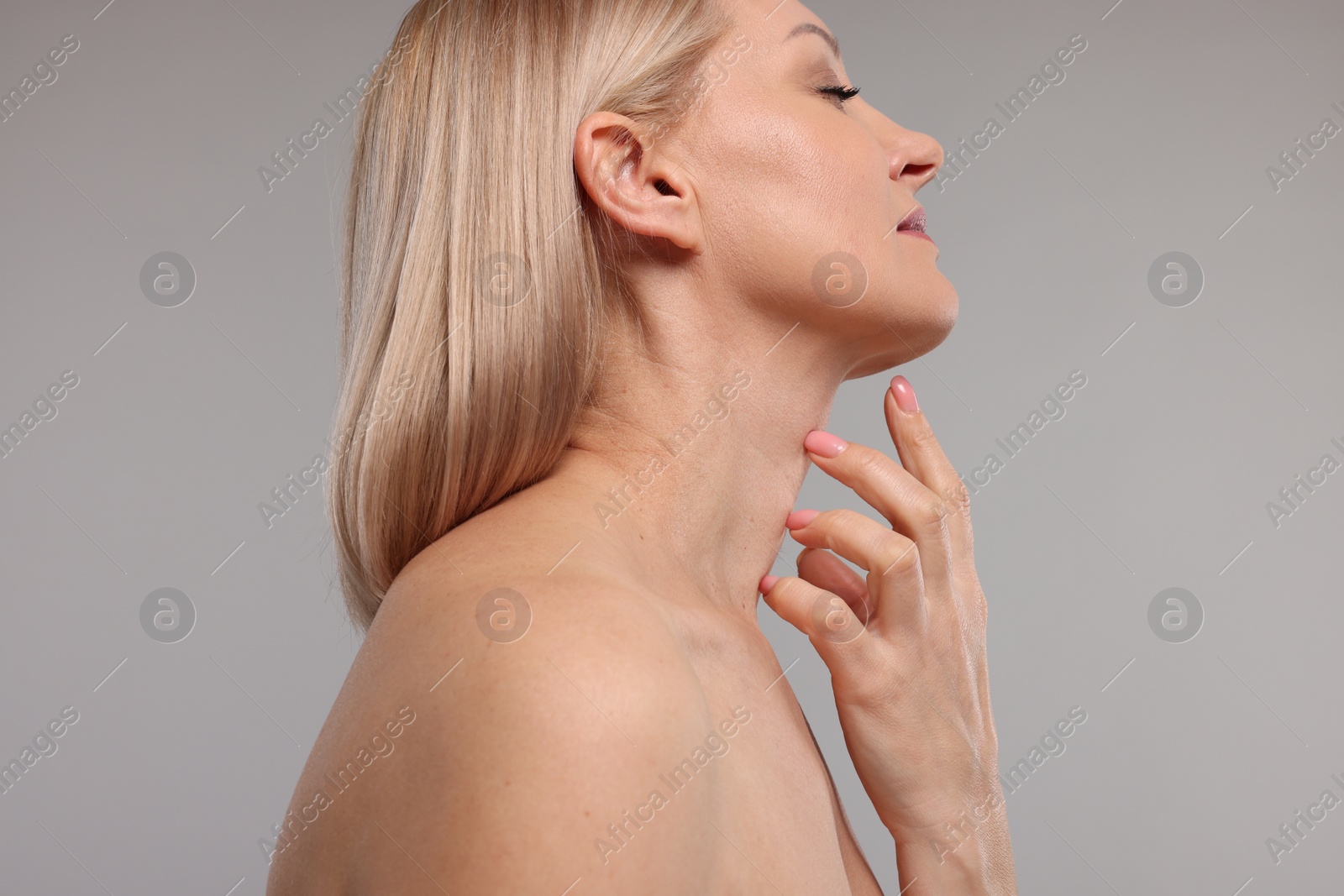 Photo of Beautiful woman touching her neck on grey background