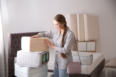 Young woman choosing mattress in furniture store