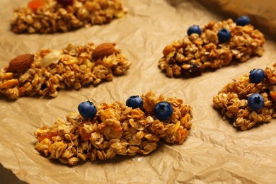 Photo of Different granola bars on parchment paper, closeup. Healthy snack