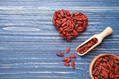 Photo of Flat lay composition with dry goji berries on blue wooden table. Space for text