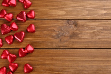 Heart shaped chocolate candies on wooden table, flat lay. Space for text