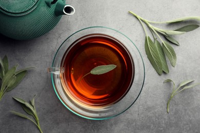 Photo of Aromatic herbal tea with sage on grey table, flat lay