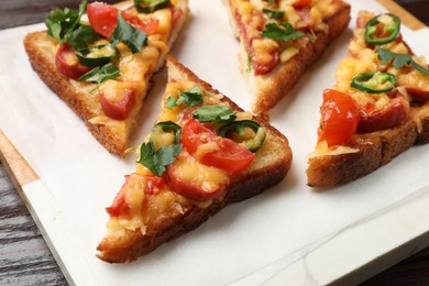 Photo of Tasty pizza toasts served on wooden table, closeup