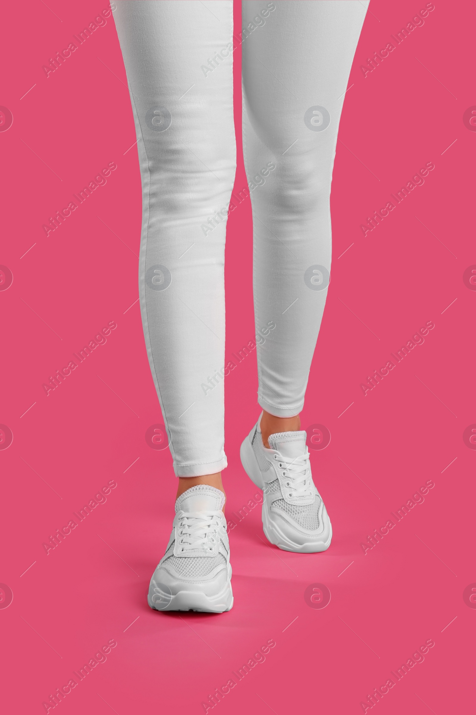 Photo of Woman wearing sneakers on pink background, closeup