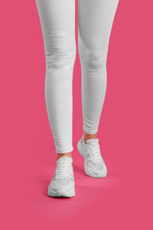 Photo of Woman wearing sneakers on pink background, closeup