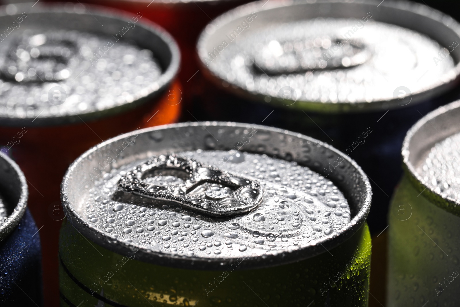 Photo of Aluminum cans of beverage covered with water drops as background, closeup