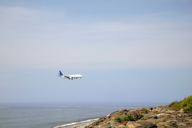 Photo of Airplane flying in blue sky over sea. Space for text