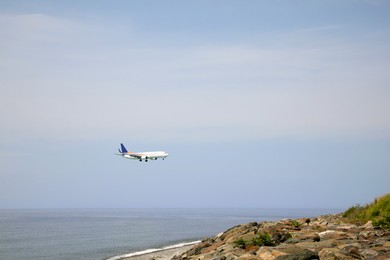 Airplane flying in blue sky over sea. Space for text