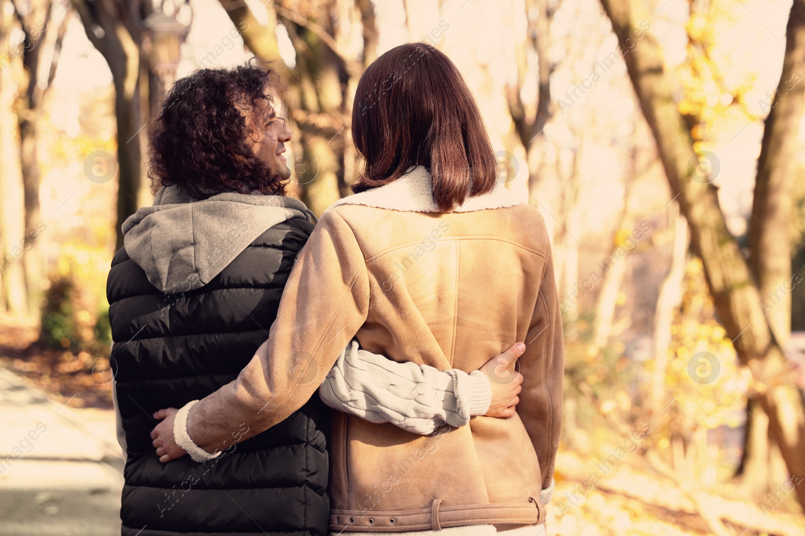 Photo of Young couple walking in autumn park, back view. Dating agency