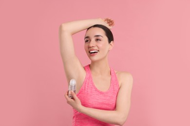 Photo of Beautiful woman applying deodorant on pink background