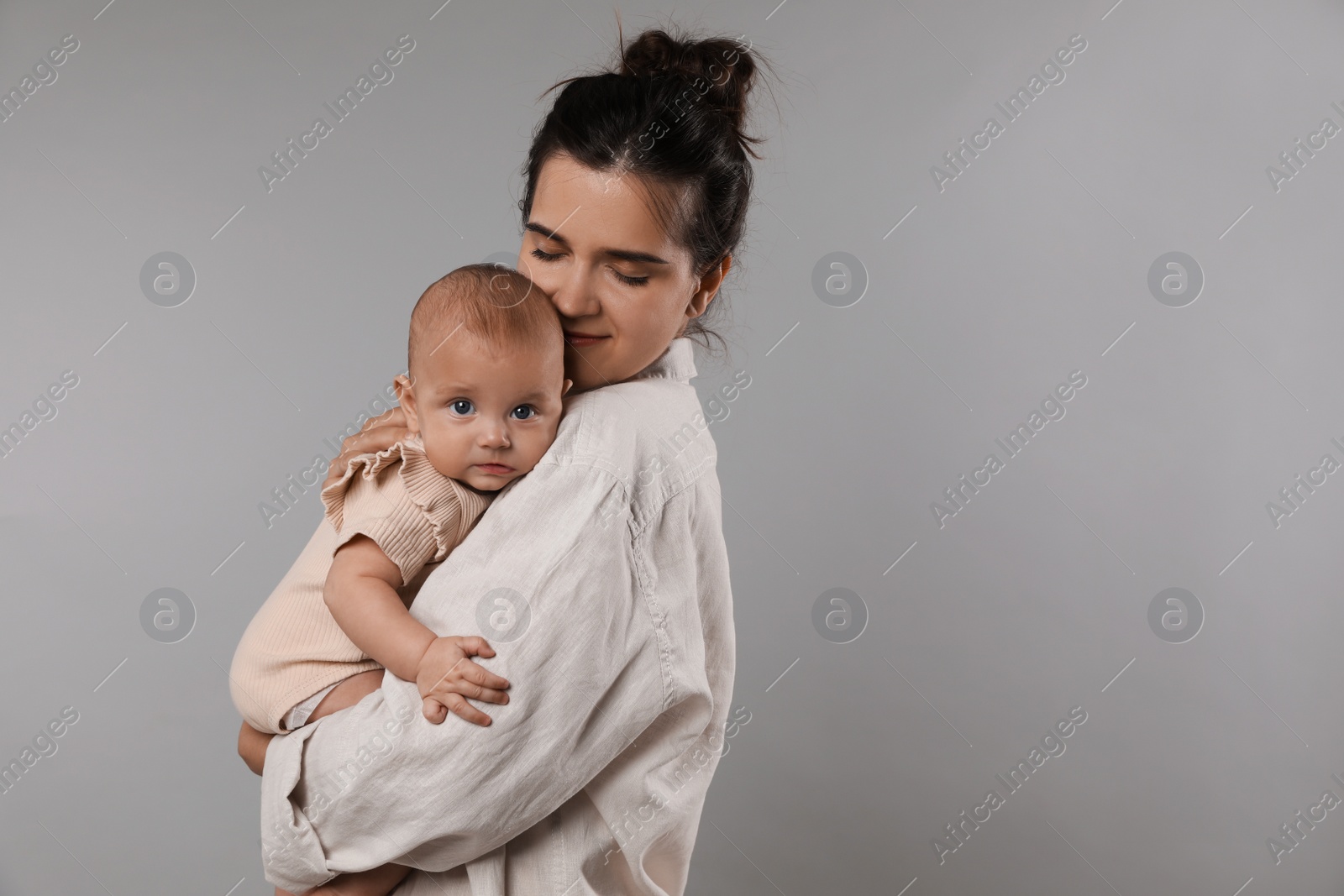 Photo of Beautiful mother with her cute baby on grey background. Space for text