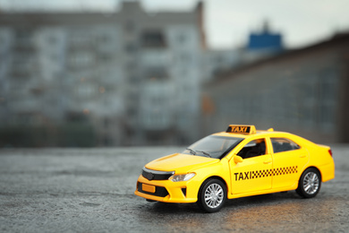 Photo of Yellow taxi car model on city street. Space for text