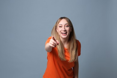 Photo of Beautiful young woman laughing on grey background. Funny joke