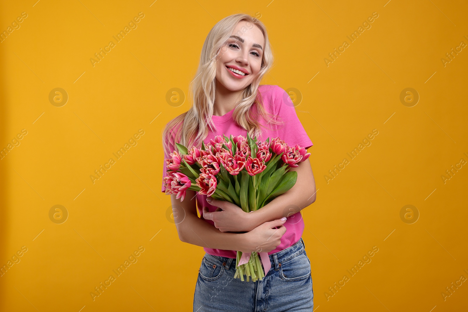 Photo of Happy young woman with beautiful bouquet on orange background