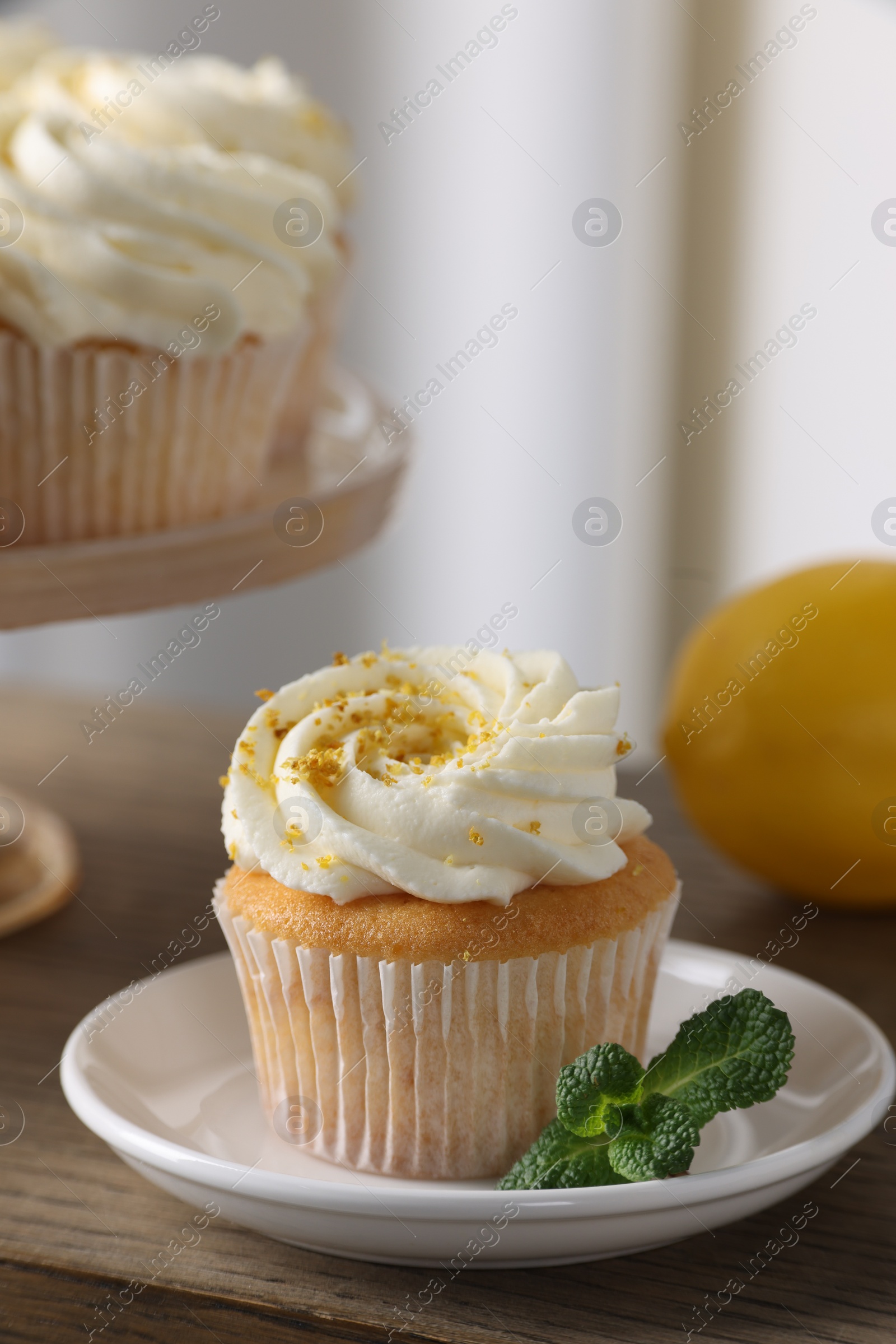 Photo of Delicious lemon cupcakes with white cream and mint on table, closeup