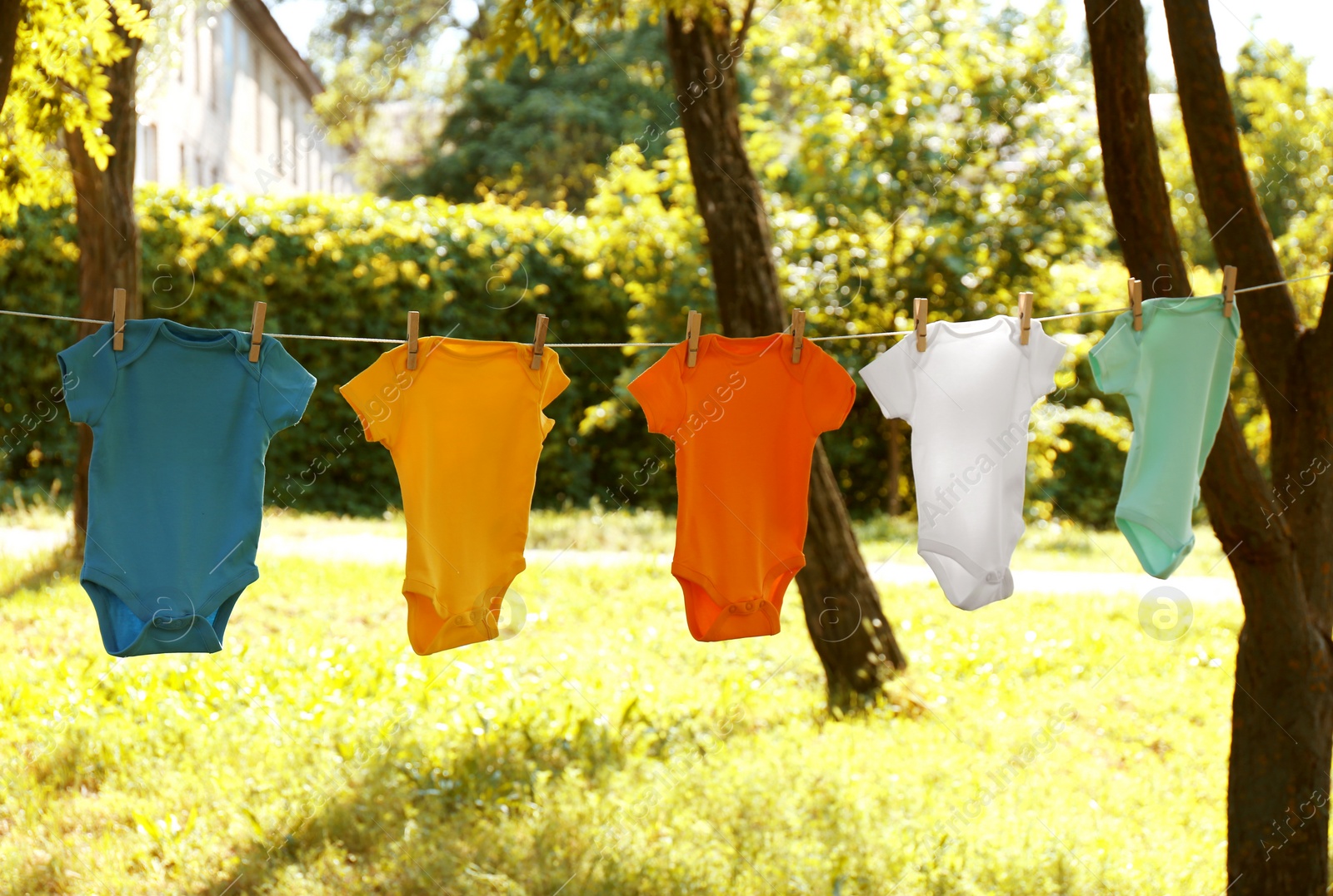 Photo of Colorful baby onesies hanging on clothes line outside