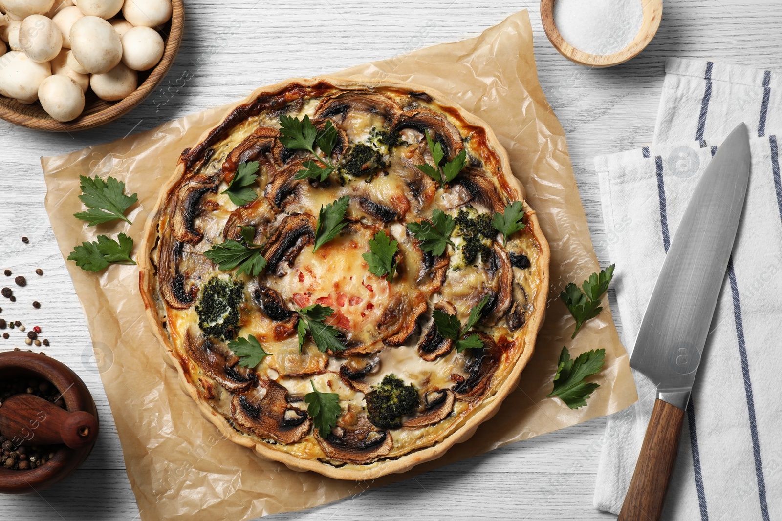 Photo of Delicious quiche with mushrooms and ingredients on white wooden table, flat lay