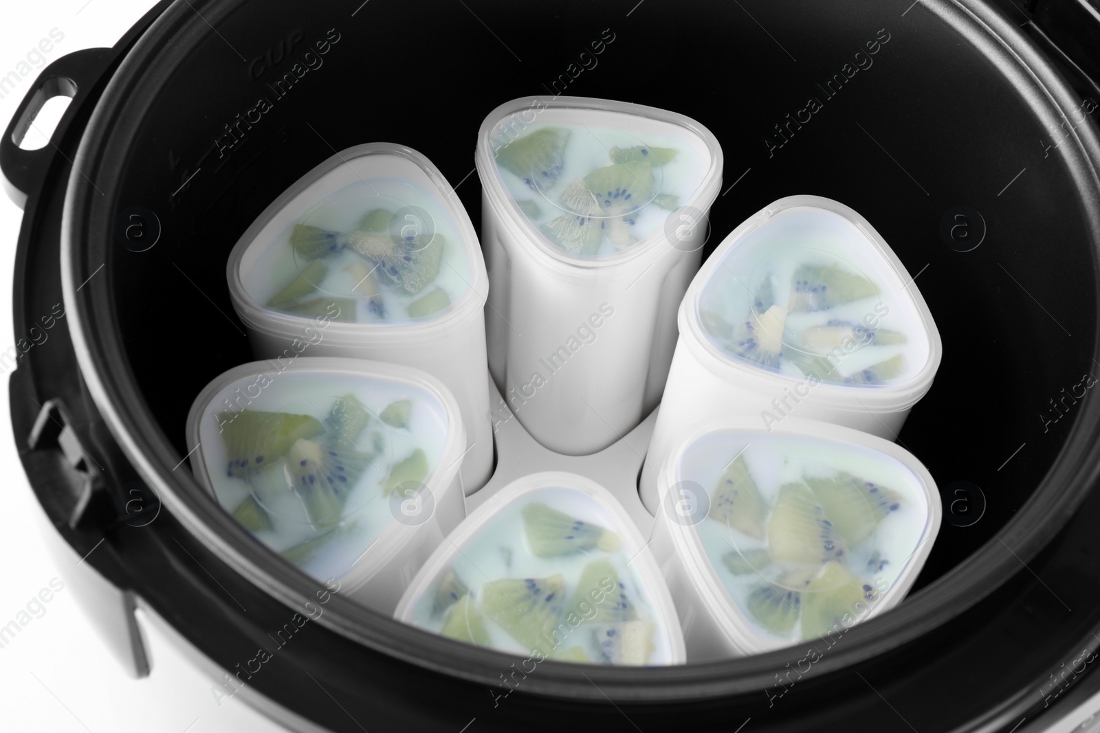Photo of Cups of homemade kiwi yogurt in modern multi cooker on white background