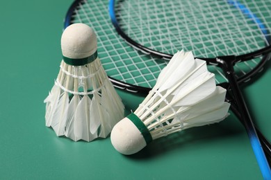 Feather badminton shuttlecocks and rackets on green background, closeup