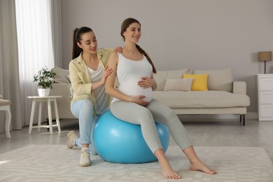 Doula working with pregnant woman in living room. Preparation for child birth