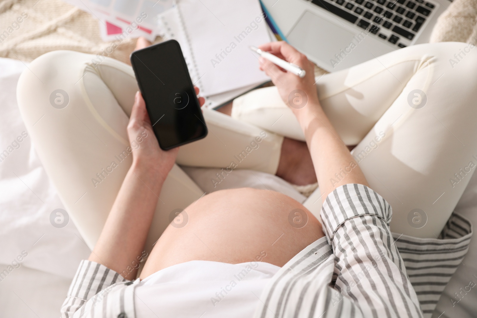 Photo of Pregnant woman working on bed at home, above view. Maternity leave