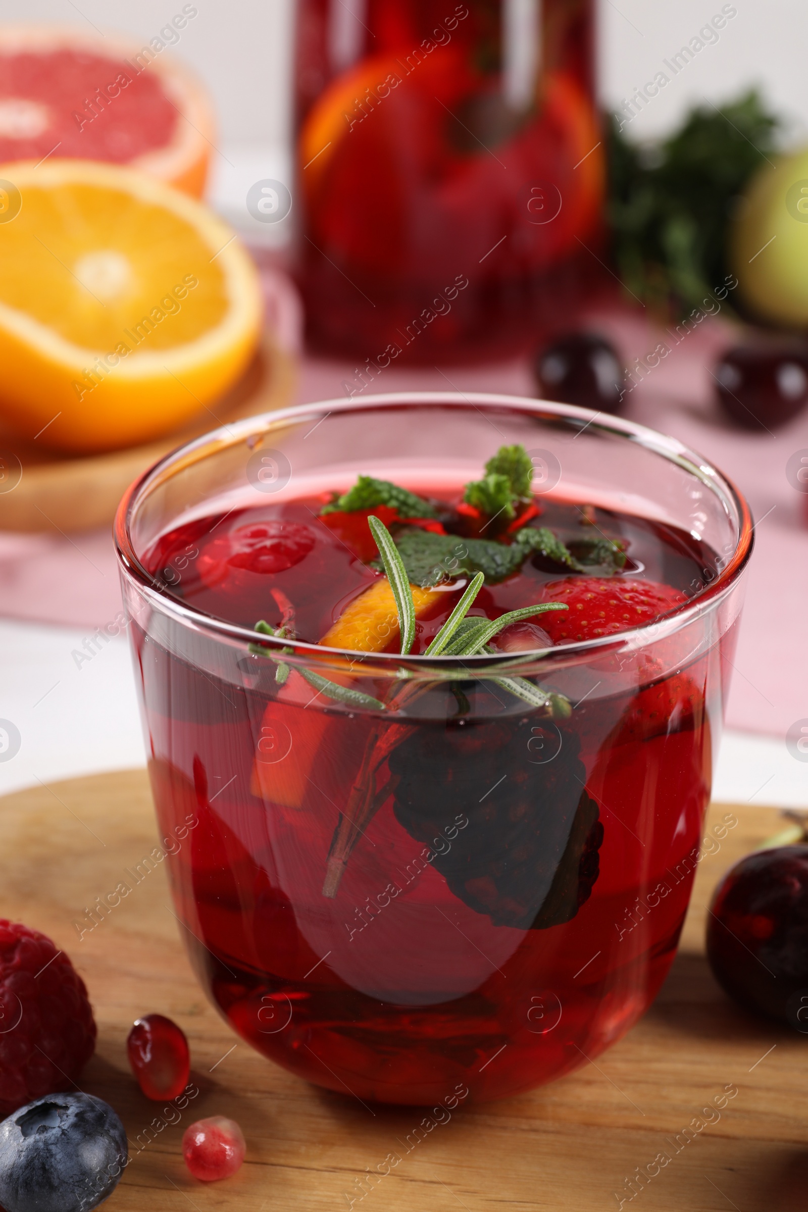 Photo of Glass of delicious refreshing sangria on wooden board, closeup