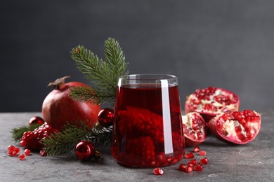 Photo of Aromatic Sangria drink in glass, Christmas decor and pomegranates on grey textured table
