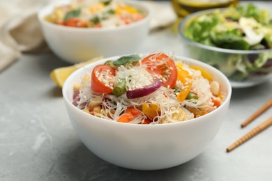 Tasty cooked rice noodles with vegetables on grey marble table