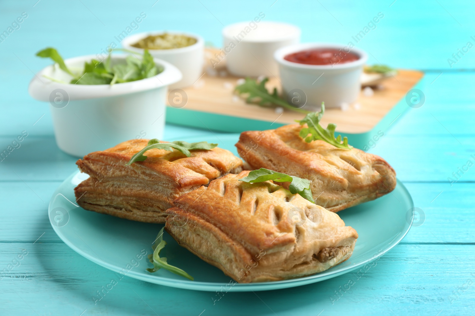 Photo of Fresh delicious puff pastry served on light blue wooden table