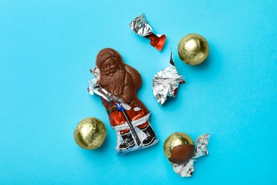 Photo of Chocolate Santa Claus and sweets on light blue background, flat lay