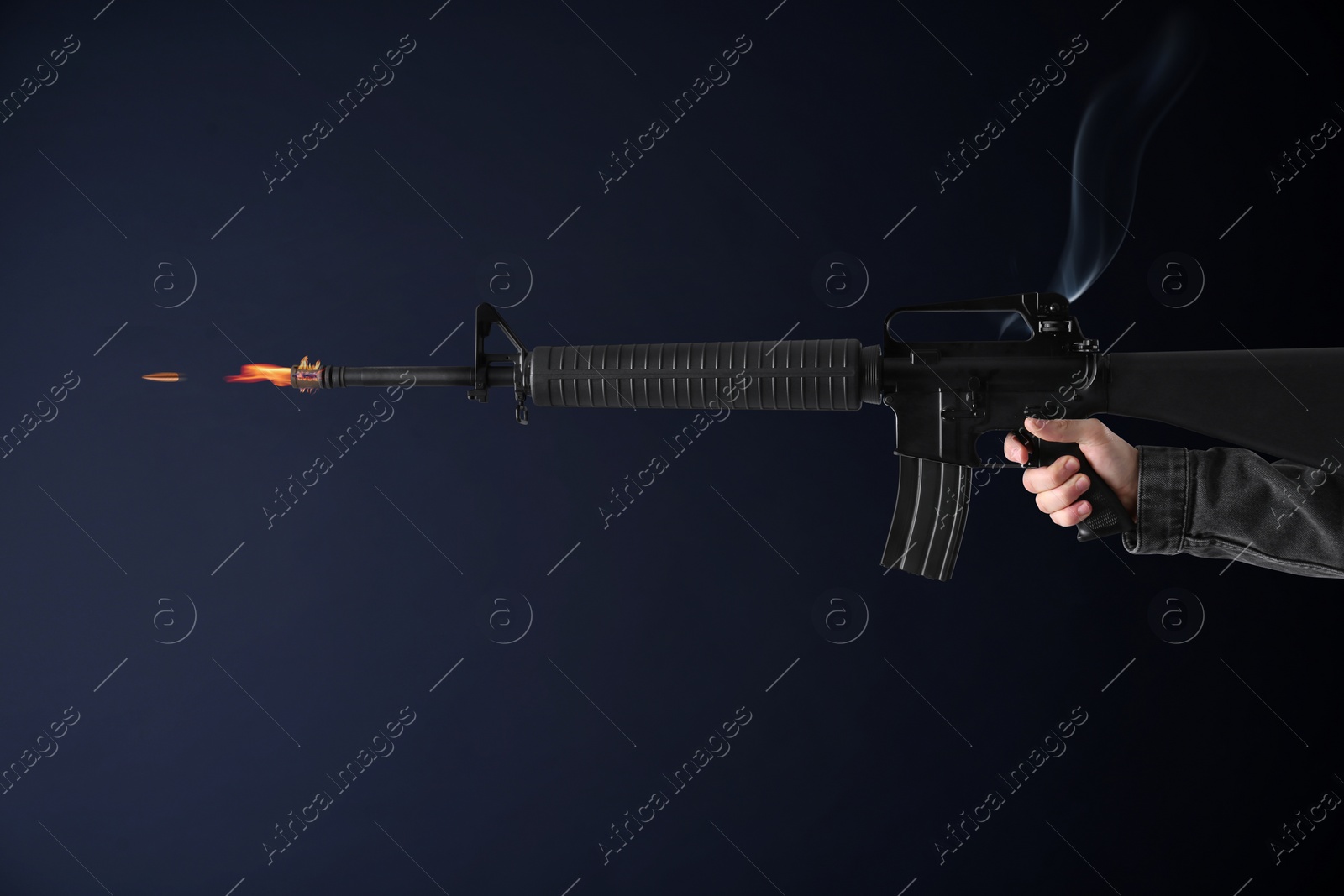 Image of Man shooting from assault rifle on dark background, closeup