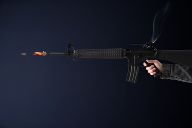 Image of Man shooting from assault rifle on dark background, closeup