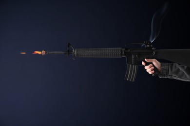 Man shooting from assault rifle on dark background, closeup