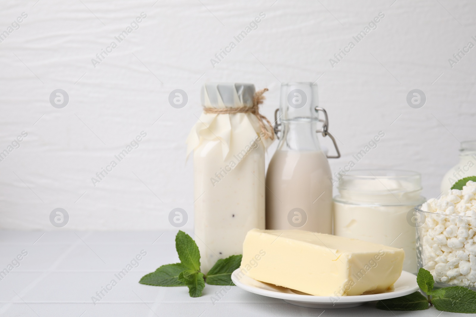 Photo of Different dairy products and mint on white table, space for text