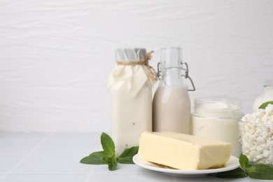 Different dairy products and mint on white table, space for text