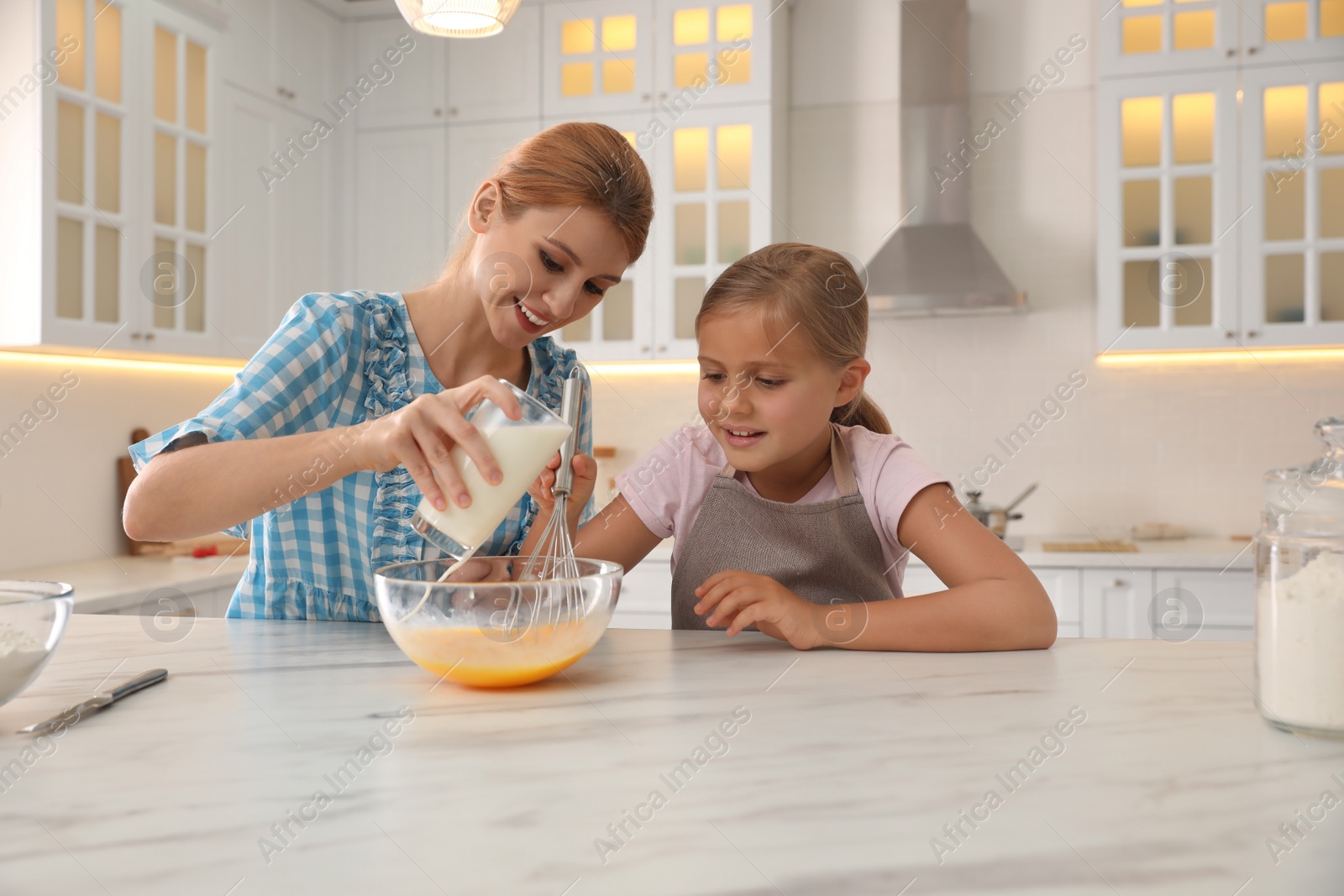 Photo of Mother and daughter making dough together in kitchen