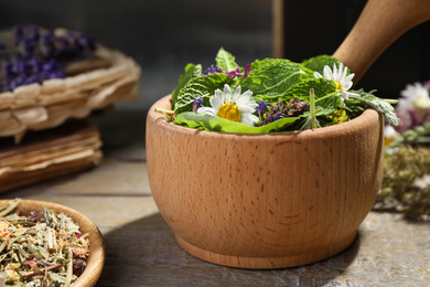 Mortar with healing herbs and pestle on wooden table