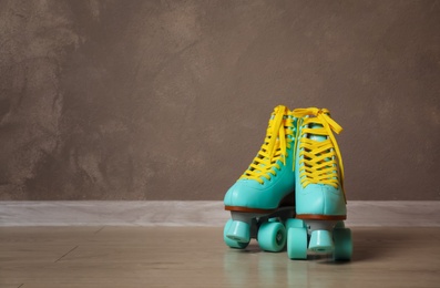 Photo of Vintage roller skates on floor near brown wall. Space for text