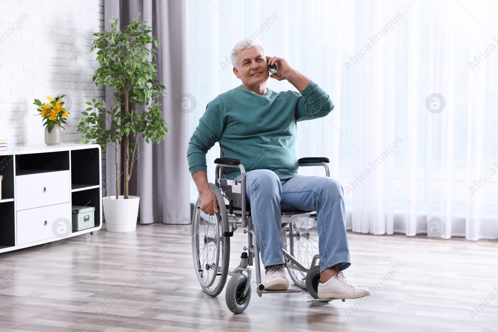 Photo of Senior man in wheelchair talking on phone at home